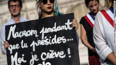 An activist holds a placard reading &quot;Macron while you preside I&#39;m dying&quot; during a demonstration dedicated to the memory of the women killed by their spouse or ex-spouse since the beginning of the year and against the violence against women, in front of the Paris city hall, on August 28.