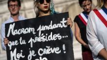 An activist holds a placard reading &quot;Macron while you preside I&#39;m dying&quot; during a demonstration dedicated to the memory of the women killed by their spouse or ex-spouse since the beginning of the year and against the violence against women, in front of the Paris city hall, on August 28.