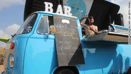 A barman serves drinks from a makeshift bar as Lebanese old Volkswagen car enthusiasts gather at a beach in the southern Lebanese town of Naqoura.