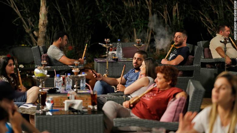 Lebanese people smoke waterpipes at a restaurant in the coastal city of Batroun north of Beirut on May 22, 2019.