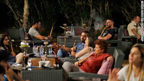 Lebanese people smoke waterpipes at a restaurant in the coastal city of Batroun north of Beirut on May 22, 2019.