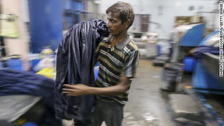 A worker unloads jeans from a fabric dyeing machine at a factory in India. (Dhiraj Singh/Bloomberg/Getty Images)