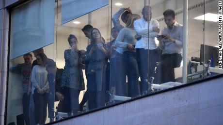 Office workers peer out of the windows of Leadenhall Market near London Bridge.