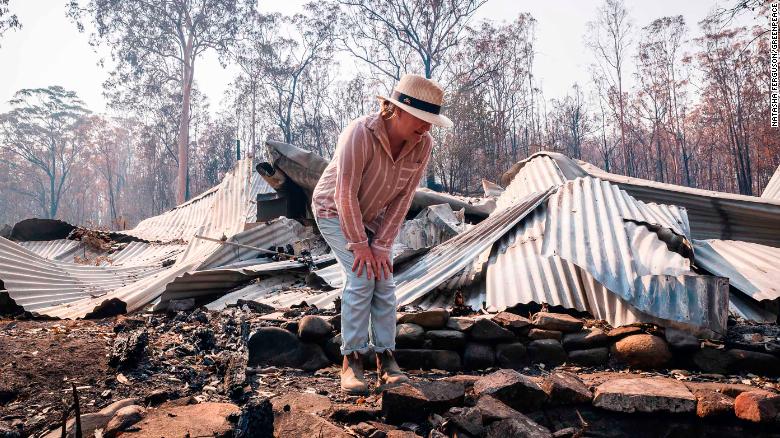 Bushfire survivor Melinda Plesman examines the remains of her destroyed property in Nymboida, NSW.