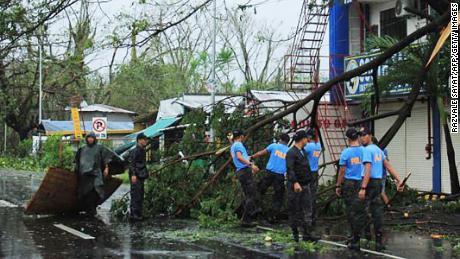 Policemen remove branches from a damaged tree following the passage of Typhoon Kammuri south of Manila.