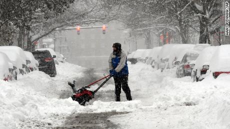 Mike Coutsonikas tries to clear sidewalks and cars of snow Monday in Albany, New York. 