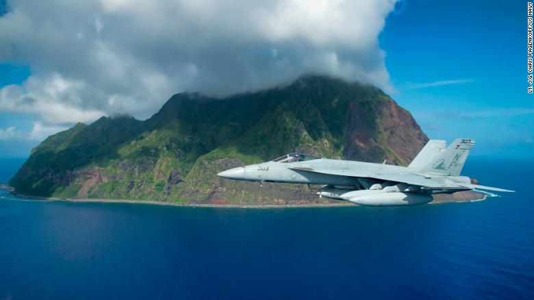 A US Navy F/A-18E Super Hornet jet flies past the island of North Iwo Jima in 2016.