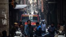 TOPSHOT - A Delhi Fire Service truck is seen along a street near the site of a facotry where a fire broke out, in Anaj Mandi area of New Delhi on December 8, 2019. - At least 43 people have died in a factory fire in India's capital New Delhi, with the toll still expected to rise, police told AFP on December 8. The blaze broke out in the early hours in the city's old quarter, whose narrow and congested lanes are lined with many small manufacturing and storage units. (Photo by STR / AFP) (Photo by STR/AFP via Getty Images)