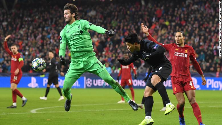 Alisson Becker claims the ball under pressure from Hwang Hee-chan .