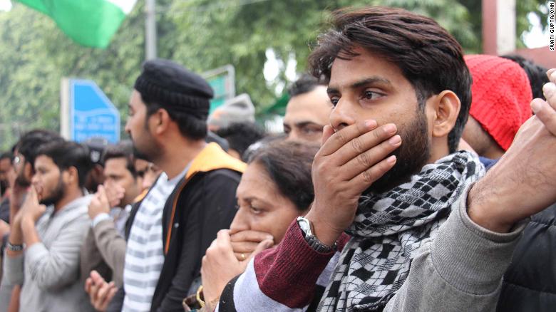 Protesters gather outside Jamia Milia Islamia University in India on Monday, covering their mouths to signify the loss of free speech in the country. 