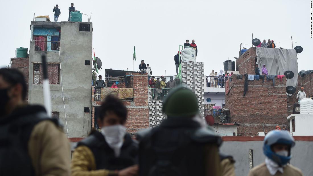 People standing on roofs in New Delhi watch police gathered next to a demonstration on December 17.