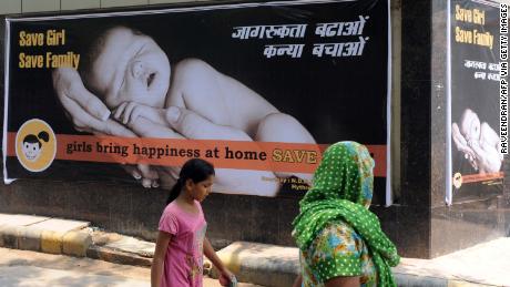 An Indian woman and child walk past a billboard in New Delhi on July 9, 2010, encouraging the birth of girls.