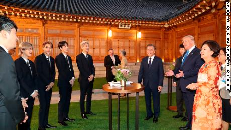 President Donald Trump talks with South Korean boy band EXO as South Korean President Moon Jae-in stands during a dinner at the presidential Blue House on June 29, 2019 in Seoul, South Korea. 