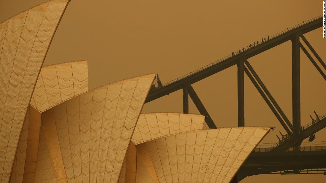 People join a guided climb of the Sydney Harbour Bridge as bushfire haze darkens the sky on December 6.