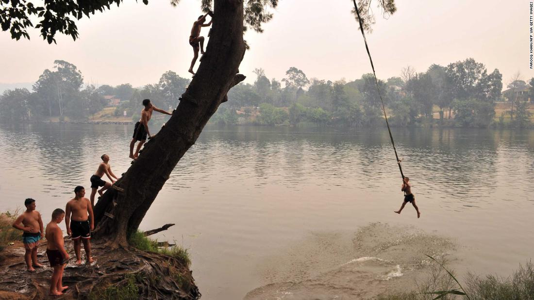 Children swing into the Penrith river during a heatwave in Sydney on December 19.