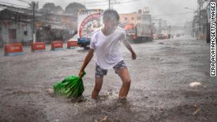 A resident clears garbage floating in a flooded highway during the onslaught of Typhoon Kammuri on December 3, 2019 in Lipa town, Batangas province, Philippines. 