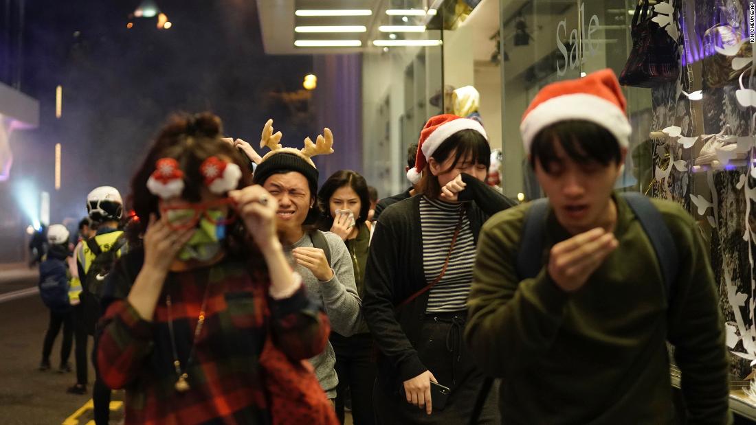 People celebrating the holidays react to tear gas as police confront protesters on Christmas Eve.