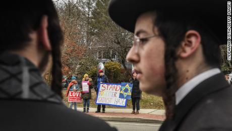  People hold signs of support near the house of Rabbi Chaim Rottenberg