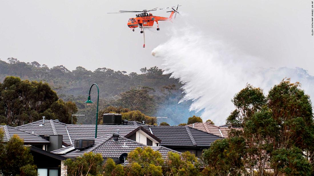 A skycrane drops water on a bushfire burning near houses in Bundoora, Melbourne, on Monday, December 30.