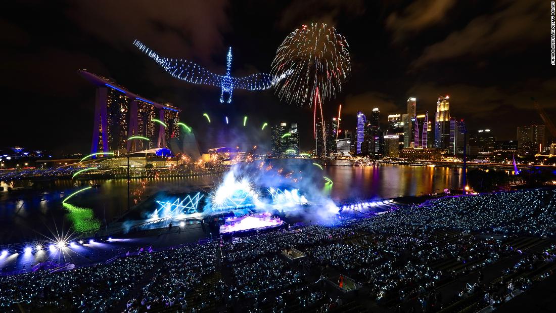 Drones form the shape of a crane in the sky as fireworks erupt at Singapore&#39;s Marina Bay.