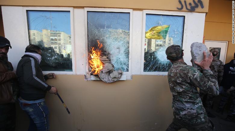 Protesters smash the bullet-proof glass of the US Embassy&#39;s windows in Baghdad on December 31.