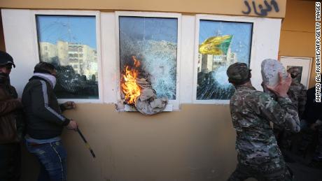 Protesters smash the bullet-proof glass of the US Embassy&#39;s windows in Baghdad on December 31.