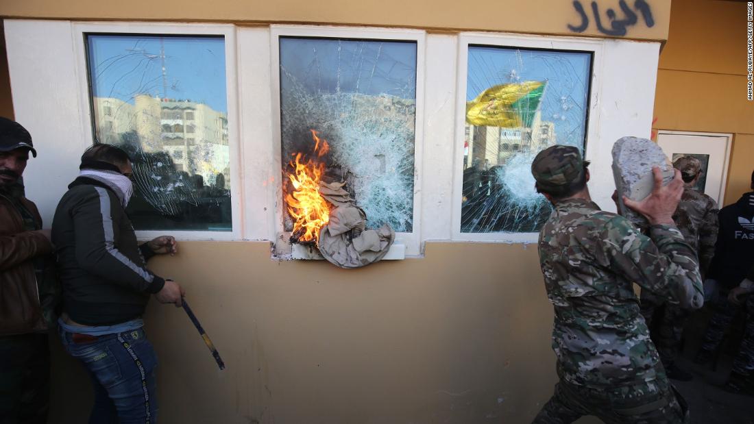Protesters and militia fighters smash the bullet-proof glass of the embassy's windows with blocks of cement after breaching the outer wall.