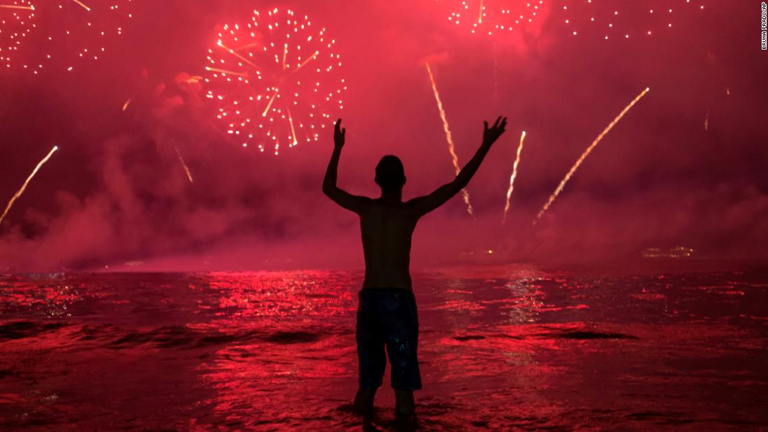 A man watches fireworks from Copacabana Beach in Rio de Janeiro, Brazil.