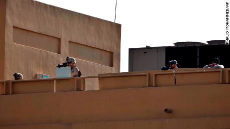 US soldiers stand guard on the roof of the US Embassy in Baghdad while pro-Iranian militiamen and their supporters protest outside the building.
