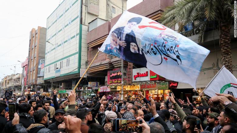 Mourners wave flags Saturday in Baghdad.