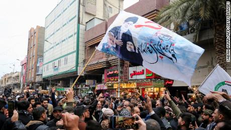 Mourners wave flags Saturday in Baghdad.
