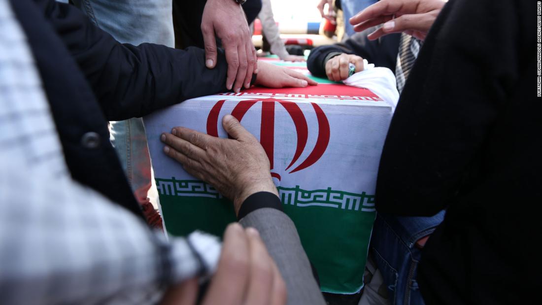 Mourners touch a casket draped in Iranian flags during Qasem Soleimani&#39;s funeral procession on January 4.