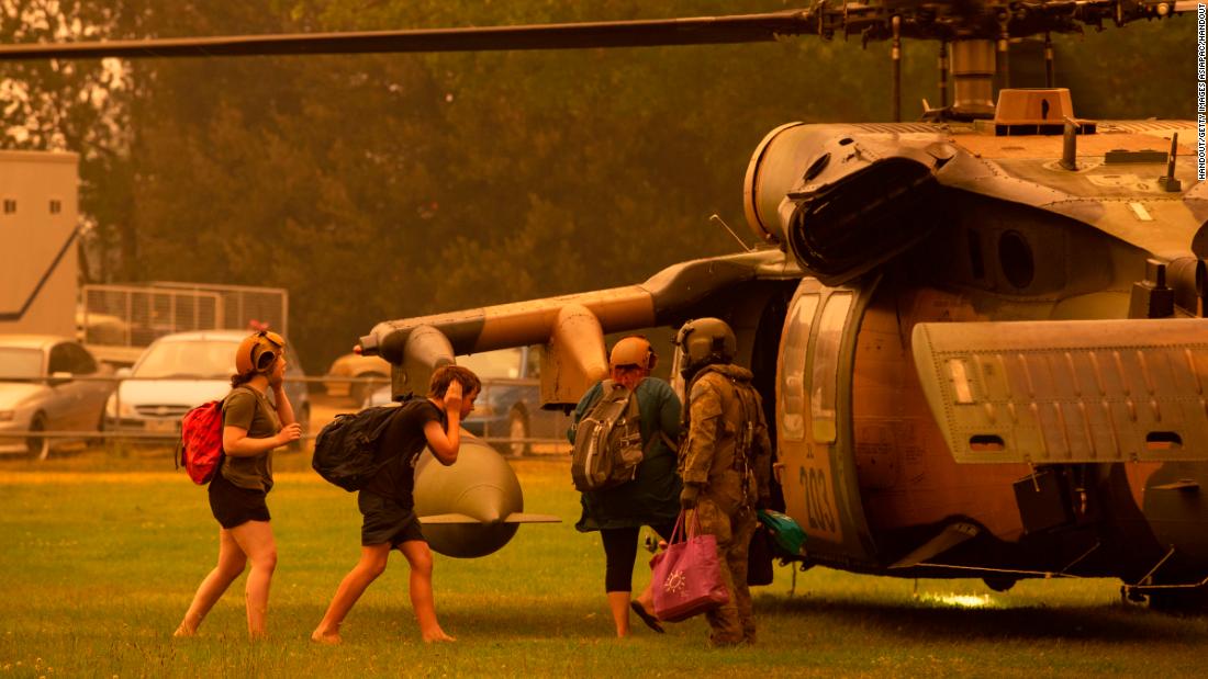 An Australian army soldier helps people evacuate onto a Black Hawk helicopter in Omeo, Victoria on January 5, 2020.