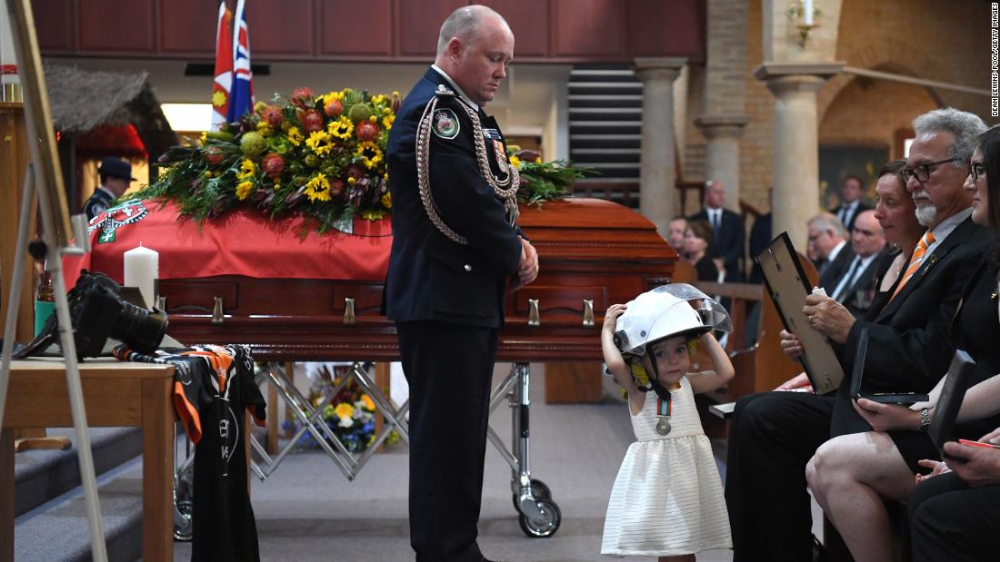 Charlotte O&#39;Dwyer, the young daughter of Rural Fire Service volunteer Andrew O&#39;Dwyer, wears her father&#39;s helmet during his funeral after being presented with a service medal in his honor by RFS Commissioner Shane Fitzsimmons on Tuesday, January 7, in Sydney.