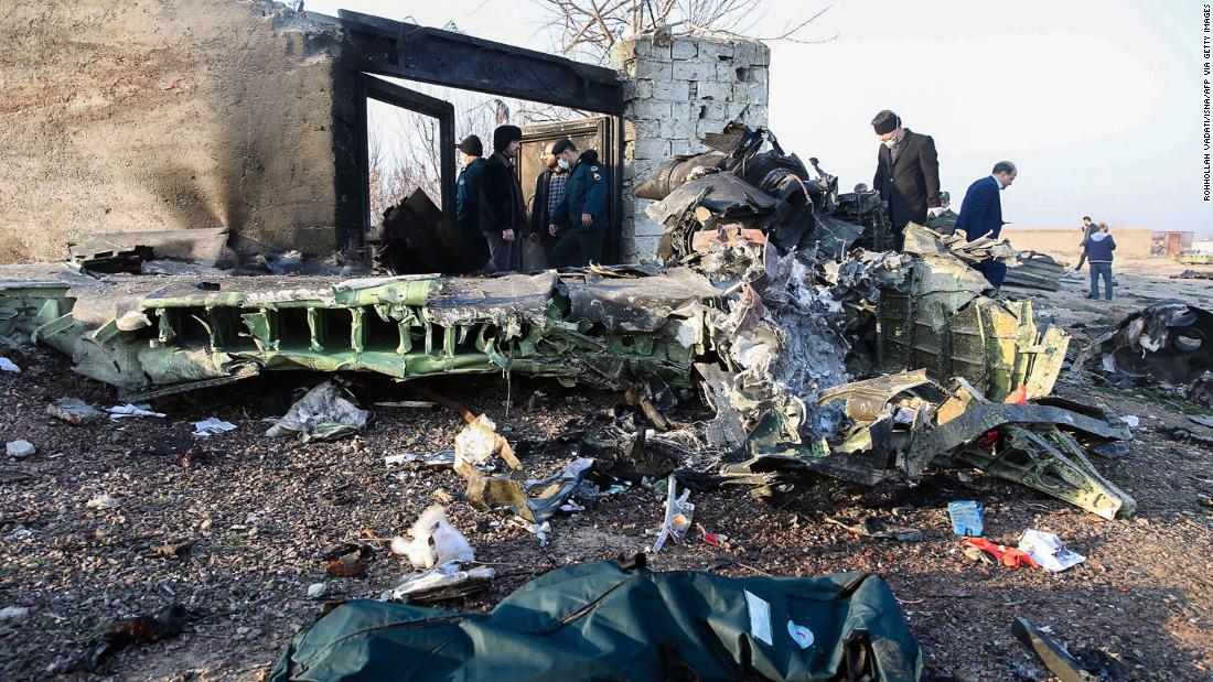 People stand near the wreckage.