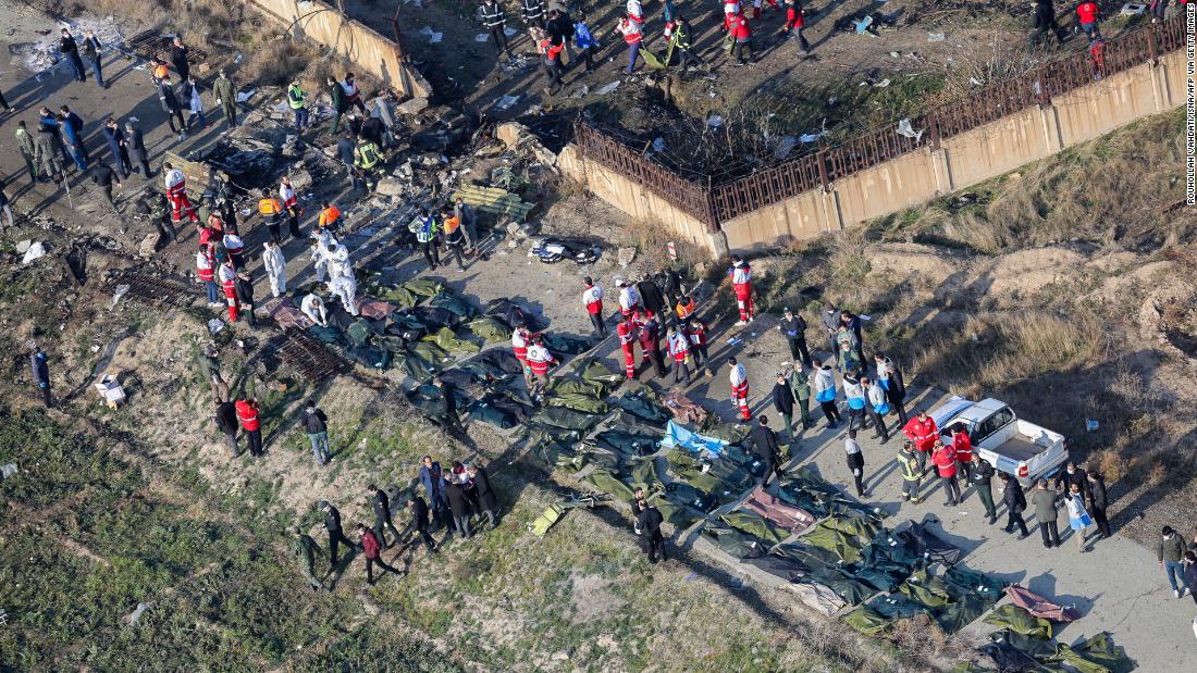 Emergency response teams and body bags are seen amid the debris.