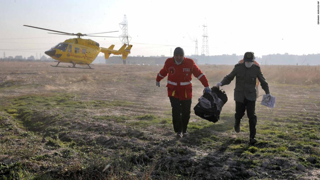 Workers carry items retrieved from the scene.