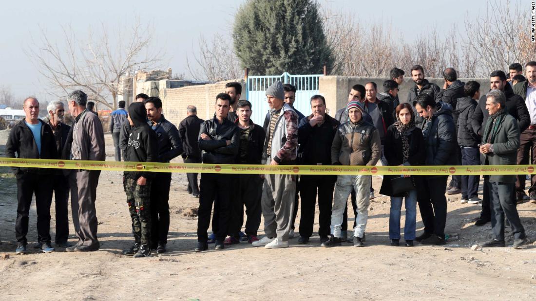 Bystanders watch as emergency teams work the crash site.