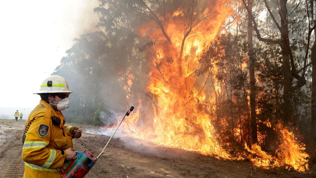 A firefighter backs away from flames after lighting a controlled burn near Tomerong on January 8.