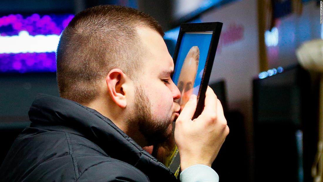 The partner of crew member Julia Sologub kisses a portrait of her at the airport memorial in Ukraine.