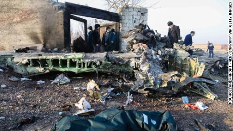 People stand near the wreckage after a Ukrainian plane carrying 176 passengers crashed near Imam Khomeini airport.