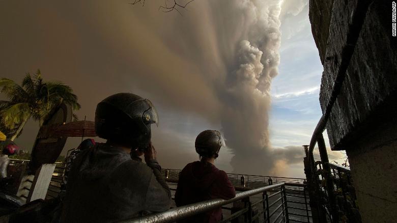 People watch plumes of smoke and ash rise from Taal Volcano on January 12, 2020, in Tagaytay outside Manila, Philippines.