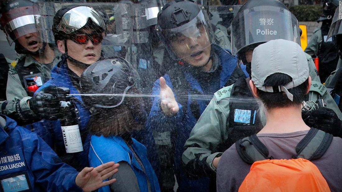 A riot policeman sprays pepper spray at a man as they disperse a crowd during a demonstration against &quot;parallel traders&quot; who buy goods in Hong Kong to resell in mainland China on Sunday, January 5.