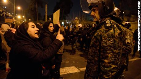 A woman attending a candlelight vigil for the victims of the Ukraine International Airlines crash, talks to a policeman following the gathering in front of the Amirkabir University in Tehran.