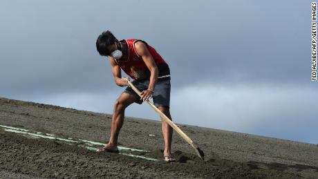 A resident cleans the roof of their house filled with ash spewed by Taal volcano in Tagaytay city.