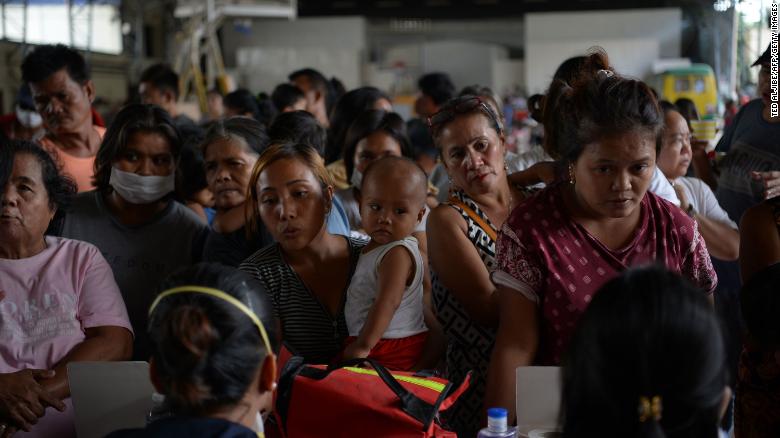 Evacuees from towns affected by the eruption of Taal volcano queue up to have their children checked by medical personnel at an evacuation center in Tanauan town.