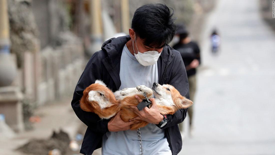 A volunteer carries a dog he rescued from deserted homes in Talisay.