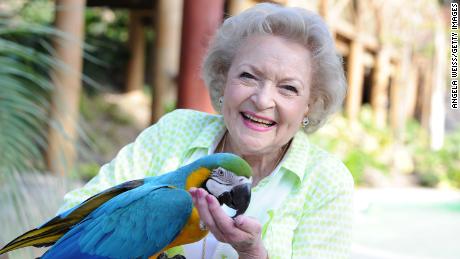 Betty White poses with a parrot. 