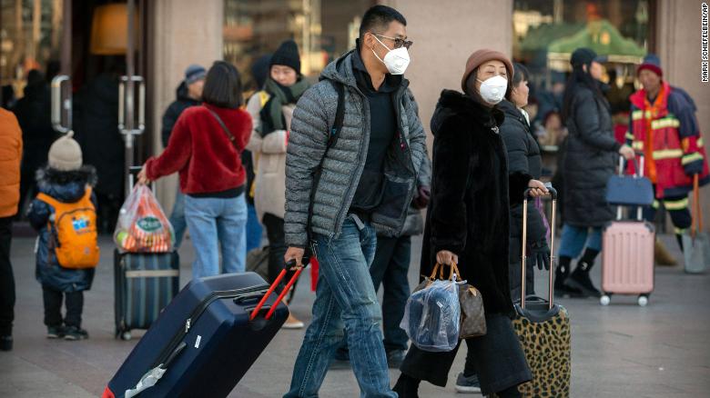 Travelers wear face masks as they walk outside of the Beijing Railway Station in Beijing, Monday, January 20, 2020.