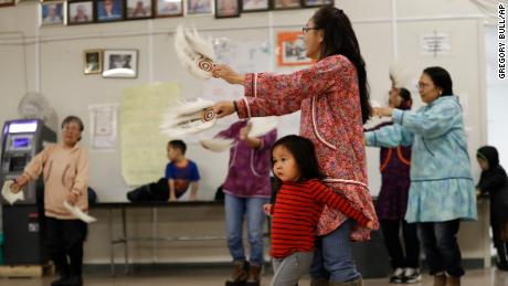 Liana Nicholai clings to her grandmother, Dora Nicholai, during an Alaska Native dance Monday in Toksook Bay.